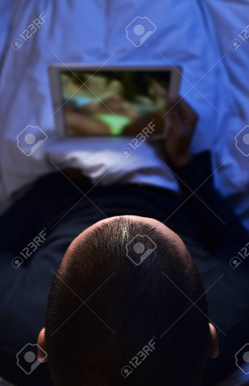 Closeup Of A Young Caucasian Man Lying In Bed And Watching Porn In His  Tablet Computer Stock Photo, Picture and Royalty Free Image. Image 57433650.