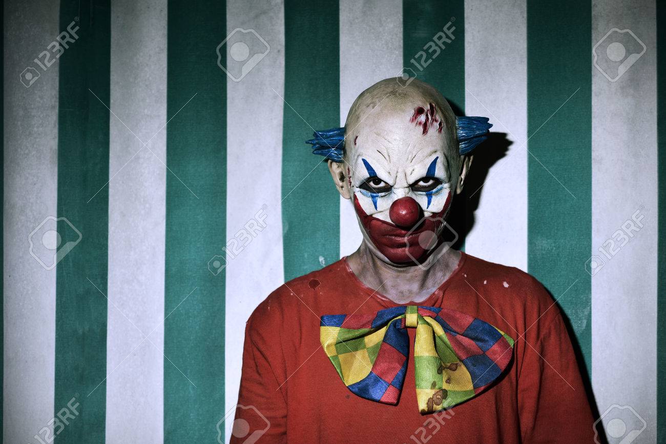 closeup of a scary evil clown wearing a dirty costume, with the circus tent in the background - 66157803 closeup of a scary evil clown wearing a dirty costume, with the circus tent in the background - 66157803