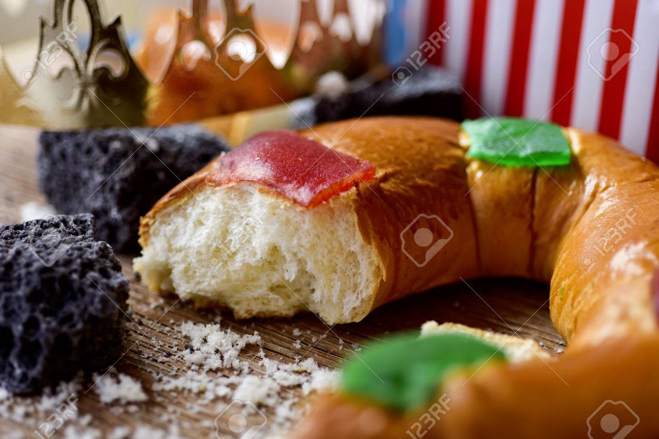 closeup of a roscon de reyes, the traditional spanish three kings cake eaten on epiphany day, and some pieces of candy coal on a rustic wooden table - 67701918 closeup of a roscon de reyes, the traditional spanish three kings cake eaten on epiphany day, and some pieces of candy coal on a rustic wooden table - 67701918