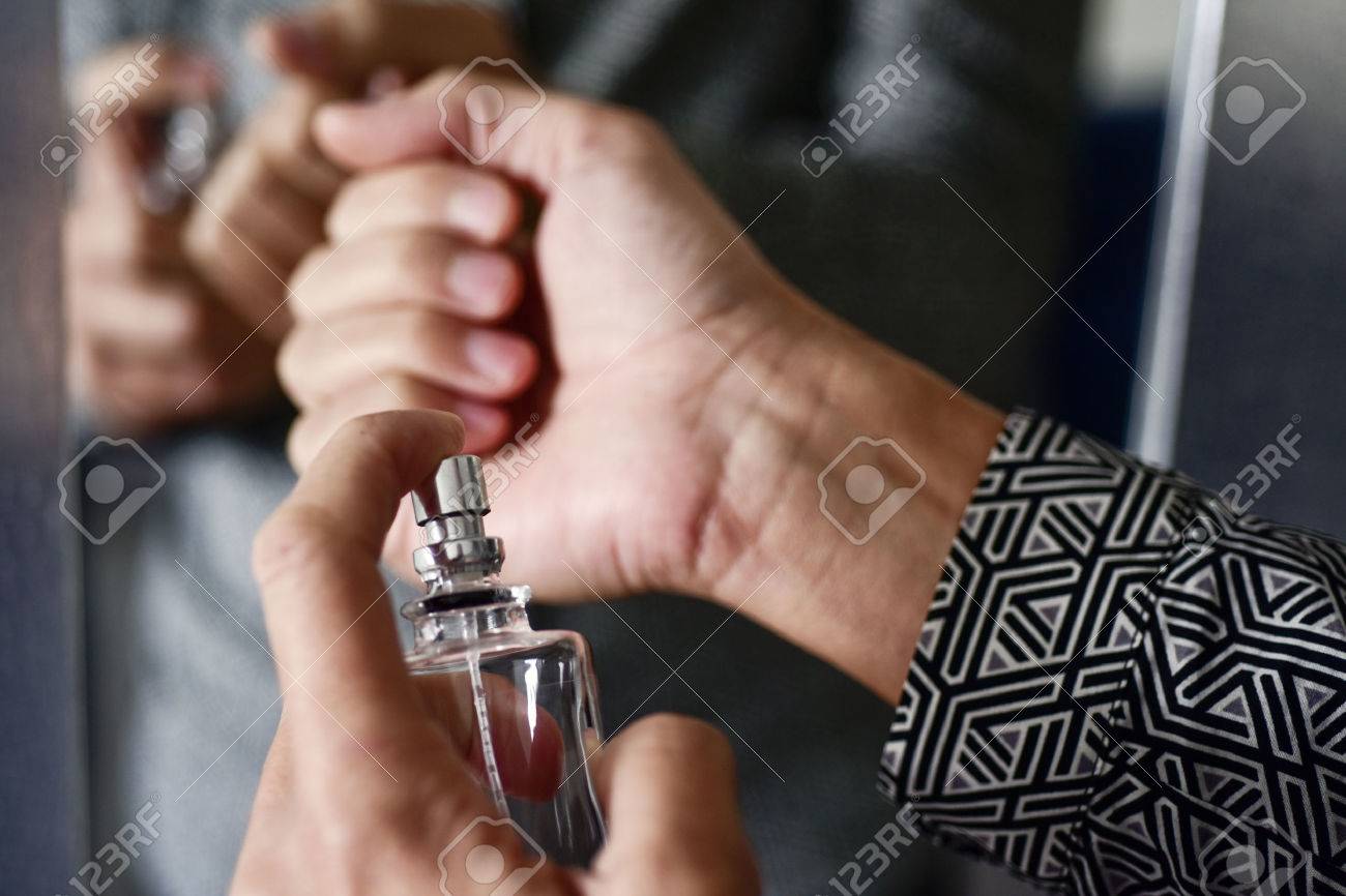 closeup of a young caucasian man spraying perfume on his wrists - 70949888 closeup of a young caucasian man spraying perfume on his wrists - 70949888