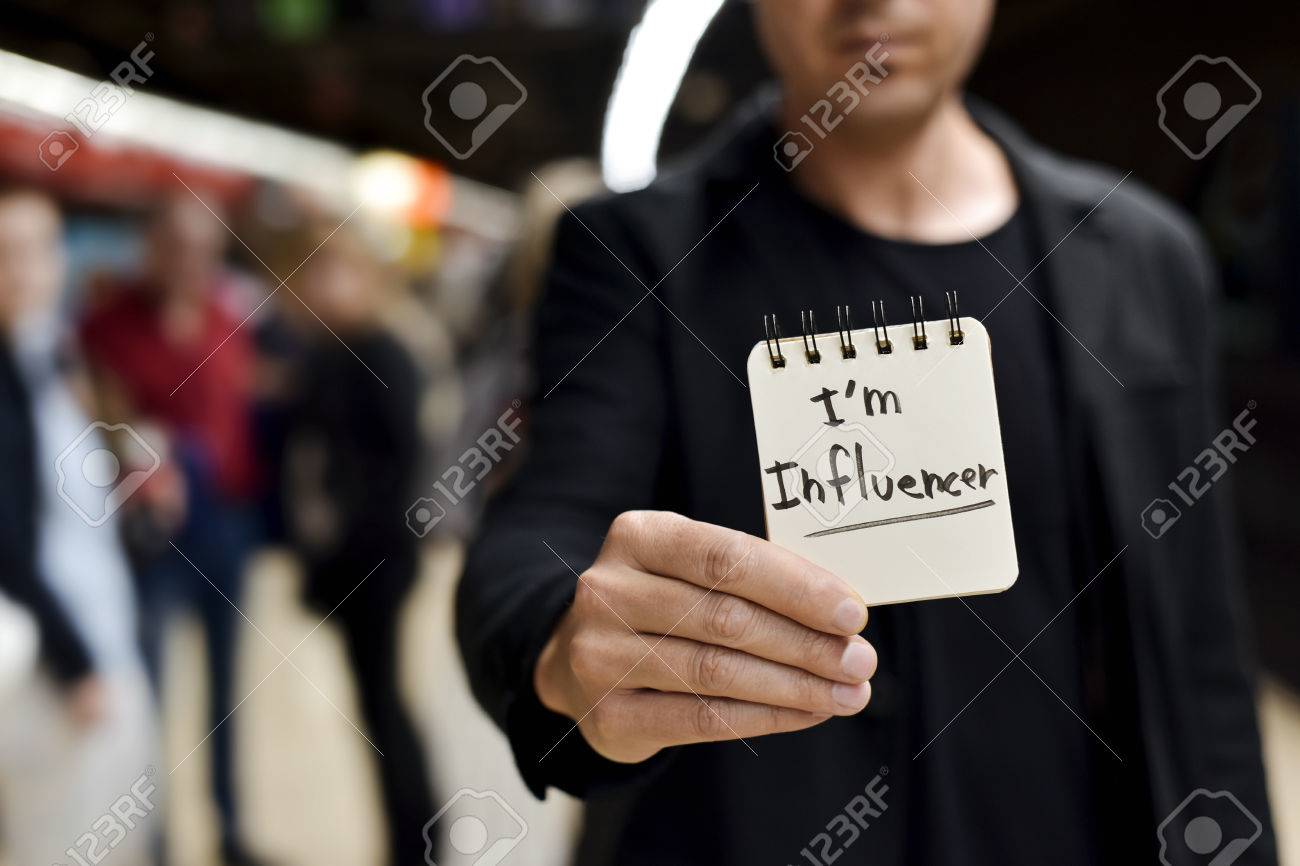 closeup of a young caucasian man in a train or metro station showing a spiral notepad with the text I am influencer written in it - 78817116 closeup of a young caucasian man in a train or metro station showing a spiral notepad with the text I am influencer written in it - 78817116
