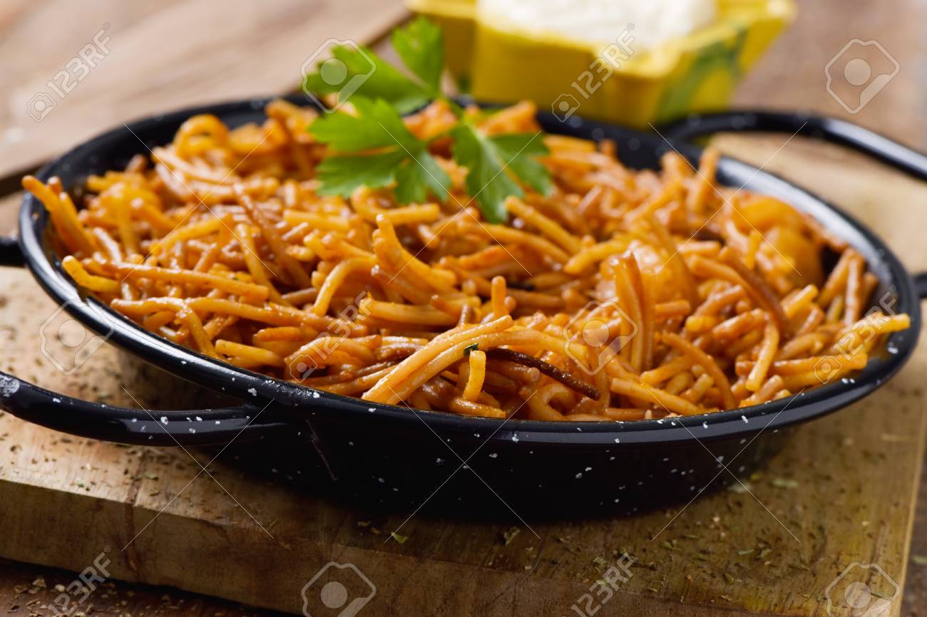 closeup of a spanish fideua, a typical noodles casserole with seafood, in a paella pan and aioli sauce in a yellow mortar on a rustic wooden table - 83022605 closeup of a spanish fideua, a typical noodles casserole with seafood, in a paella pan and aioli sauce in a yellow mortar on a rustic wooden table - 83022605