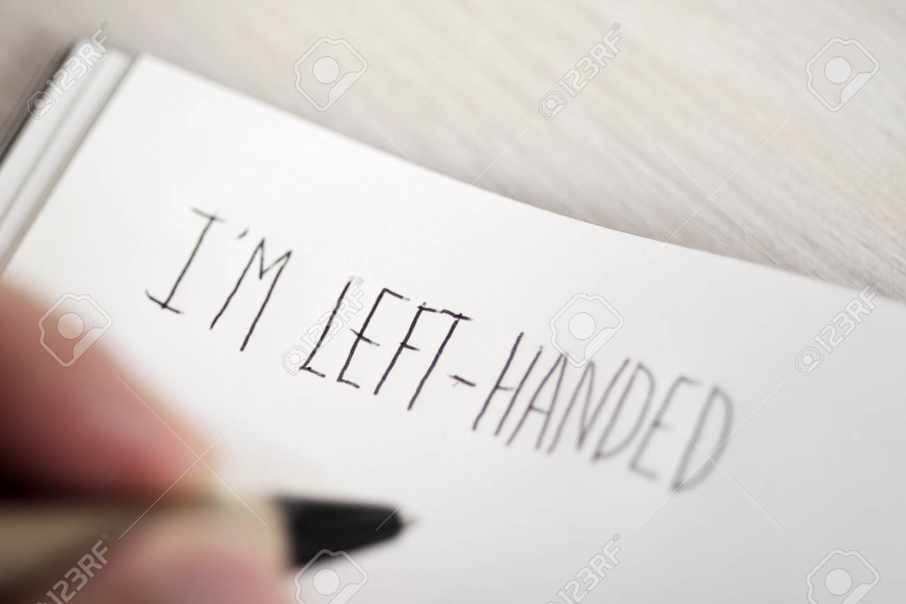 closeup of a young left-handed man handwriting the text I am left-handed in a notepad placed on a table - 83159404 closeup of a young left-handed man handwriting the text I am left-handed in a notepad placed on a table - 83159404