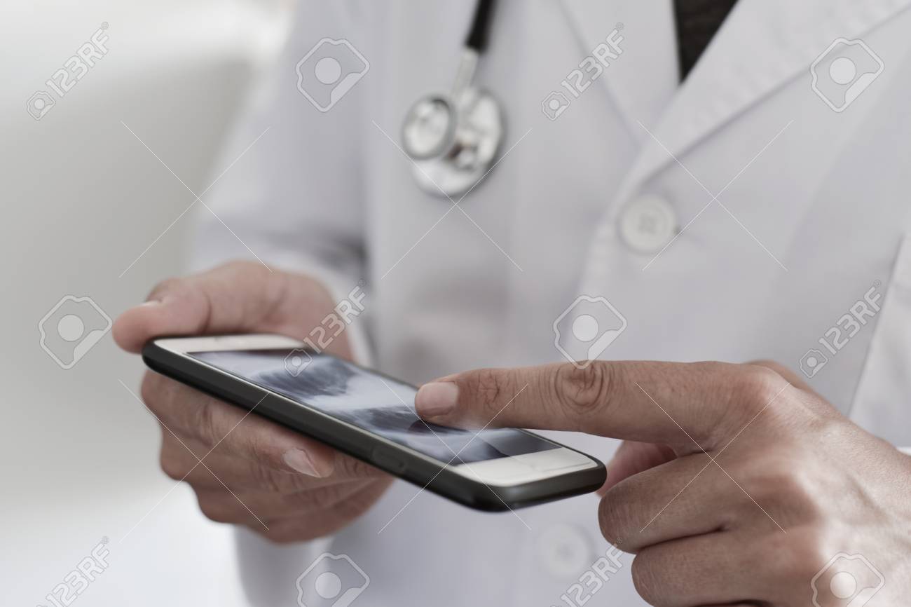 closeup of a young caucasian doctor man wearing a white coat checking a chest radiograph in a smartphone - 84723676 closeup of a young caucasian doctor man wearing a white coat checking a chest radiograph in a smartphone - 84723676