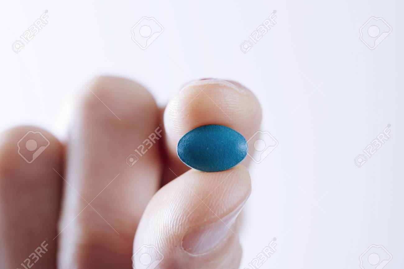 closeup of a young caucasian man with a blue pill in his hand against a white background, with some blank space - 101148568 closeup of a young caucasian man with a blue pill in his hand against a white background, with some blank space - 101148568