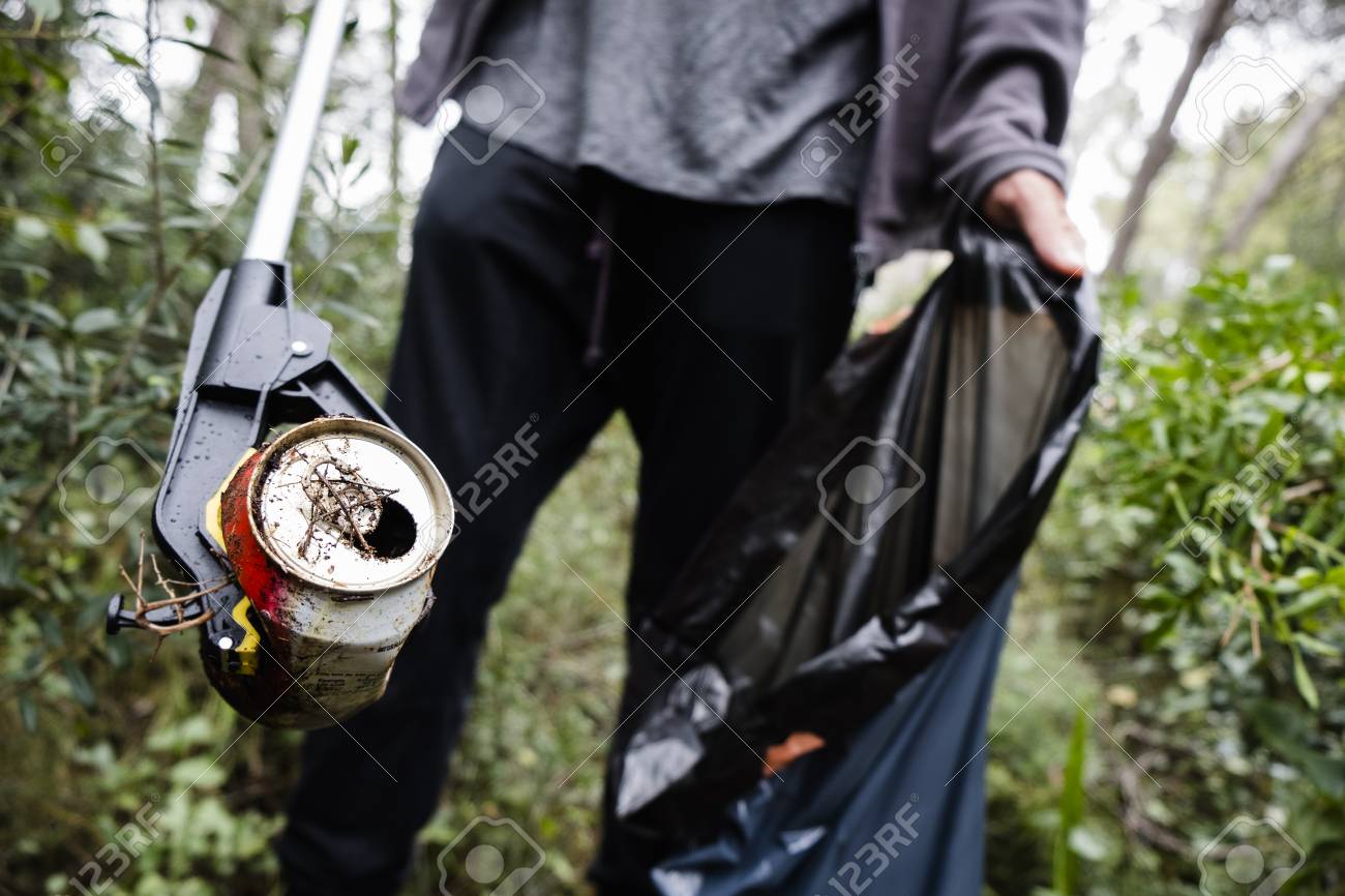 closeup of a caucasian man collecting garbage with a trash grabber stick, in a forest, as an action to clean the natural environment - 124668925 closeup of a caucasian man collecting garbage with a trash grabber stick, in a forest, as an action to clean the natural environment - 124668925