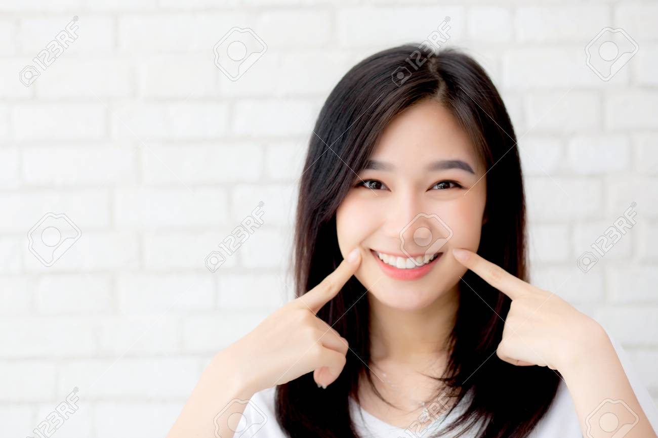 グレーのセメントテクスチャグランジ壁レンガの背景に指タッチ頬に立っている美しい若いアジアの女性の幸せの肖像画は ビジネスウーマンは コンクリート ビジネスマンのコンセプトに笑顔です の写真素材 画像素材 Image