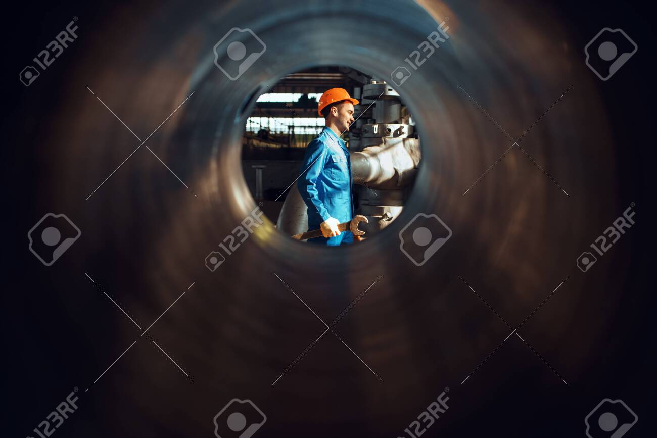 Worker with wrench on factory, view through tube - 148259406 Worker with wrench on factory, view through tube - 148259406