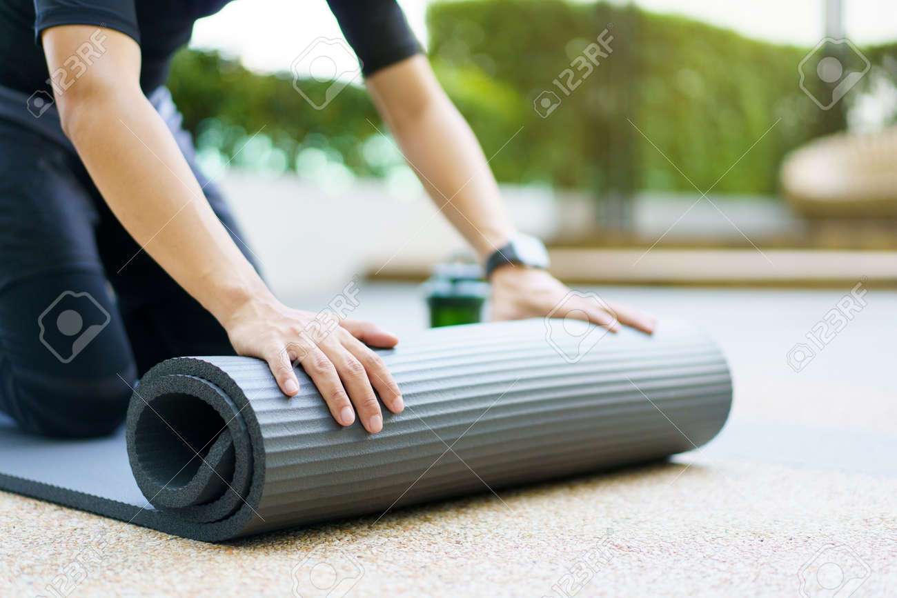 Un Deportista Asiático Activo Desenrolla Una Colchoneta De Ejercicios En El Suelo, Un Cuerpo Sano Y En Forma De Un Deportista Que Prepara Una Colchoneta De Yoga Para Peso Corporal