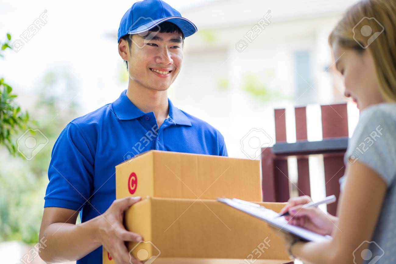 asian woman receiving a package at home from a delivery guy stock delivery person
