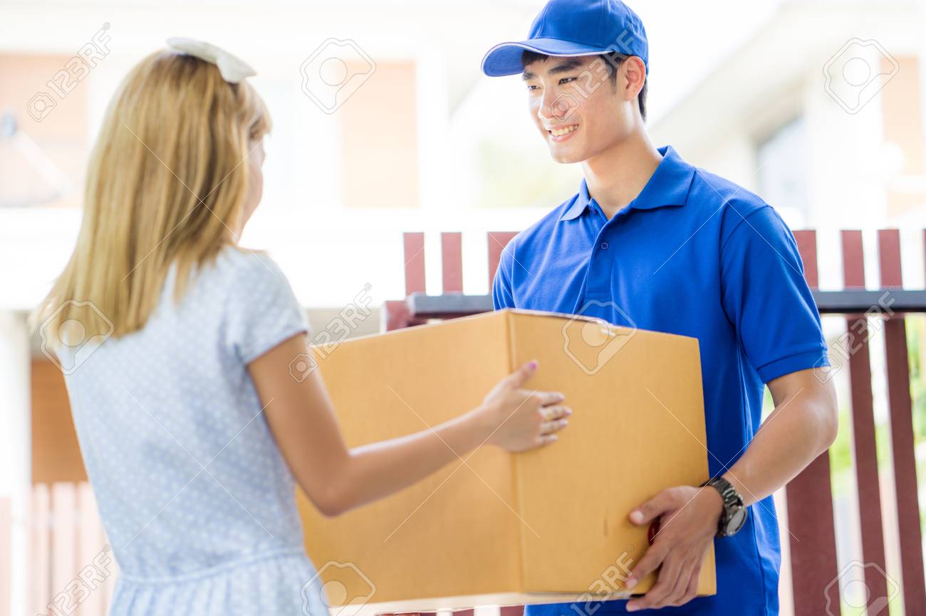 asian woman receiving a package at home from a delivery guy stock delivery person