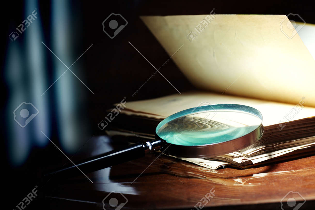 Old book and magnifier glass on a dark background as a symbol of knowledge and science - 8233909 Old book and magnifier glass on a dark background as a symbol of knowledge and science - 8233909