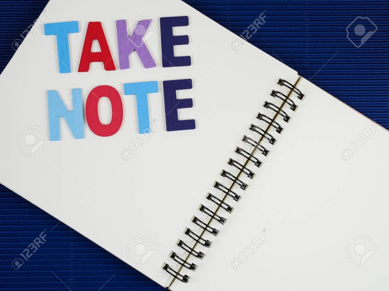 word take note on notebook with blue corrugate paper background another word for taking notes