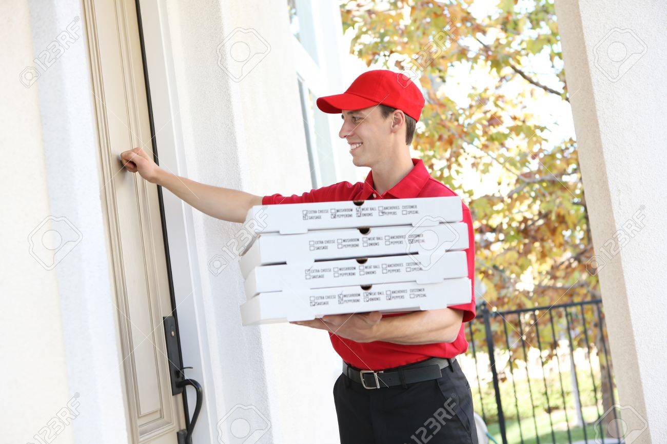 a handsome young pizza delivery man holding a pizza stock photo delivery person