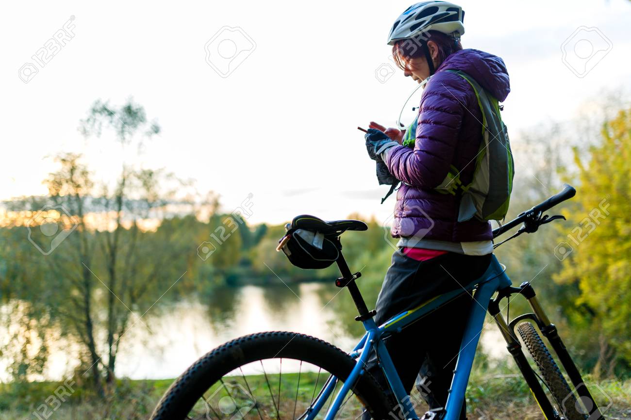 Photo De Femme Dans Le Casque Debout Avec Telephone Dans Les Mains Pres De Velo Dans Le Parc A L 39 Apres Midi Banque D Images Et Photos Libres De Droits