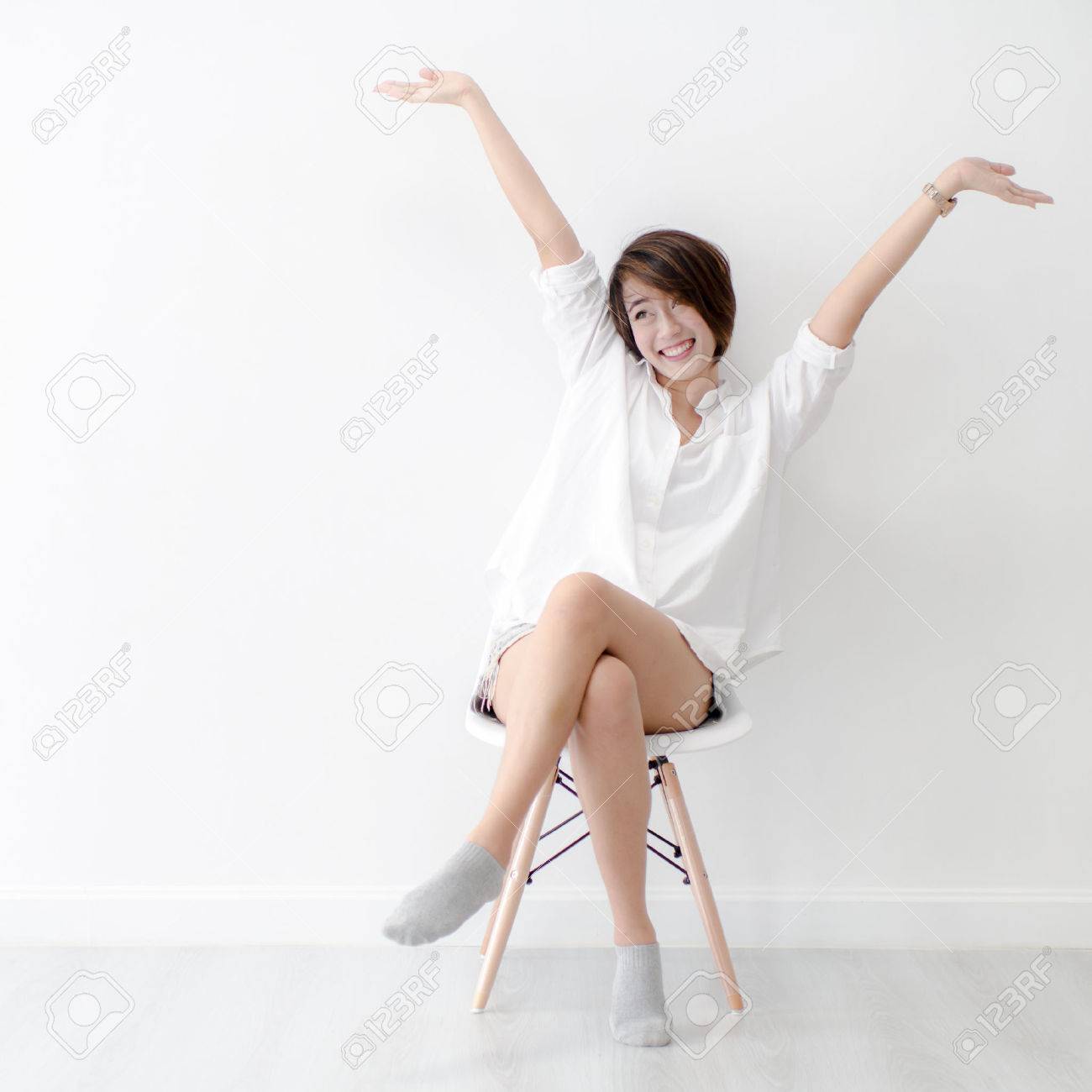 Attractive Asian girl sitting on white modern chair and relax at home. - 59147231 Attractive Asian girl sitting on white modern chair and relax at home. - 59147231