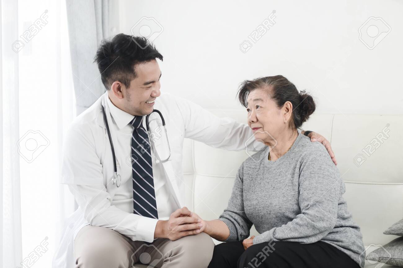 Asian doctor checking up his patient old woman in office. - 129907988 Asian doctor checking up his patient old woman in office. - 129907988