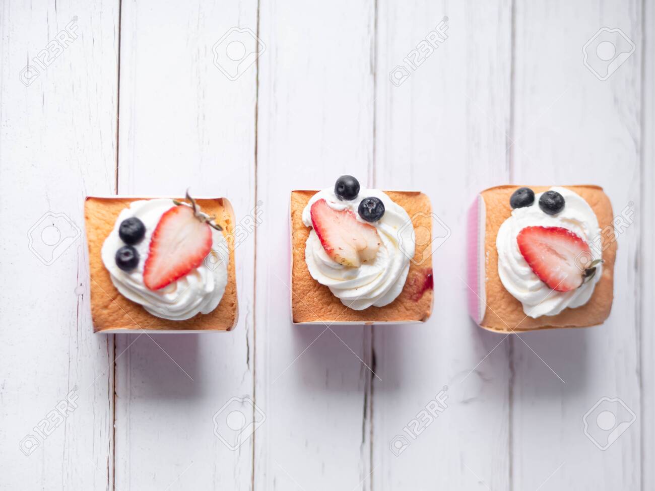Cupcakes with butter cream icing on white wooden background. - 133865388 Cupcakes with butter cream icing on white wooden background. - 133865388