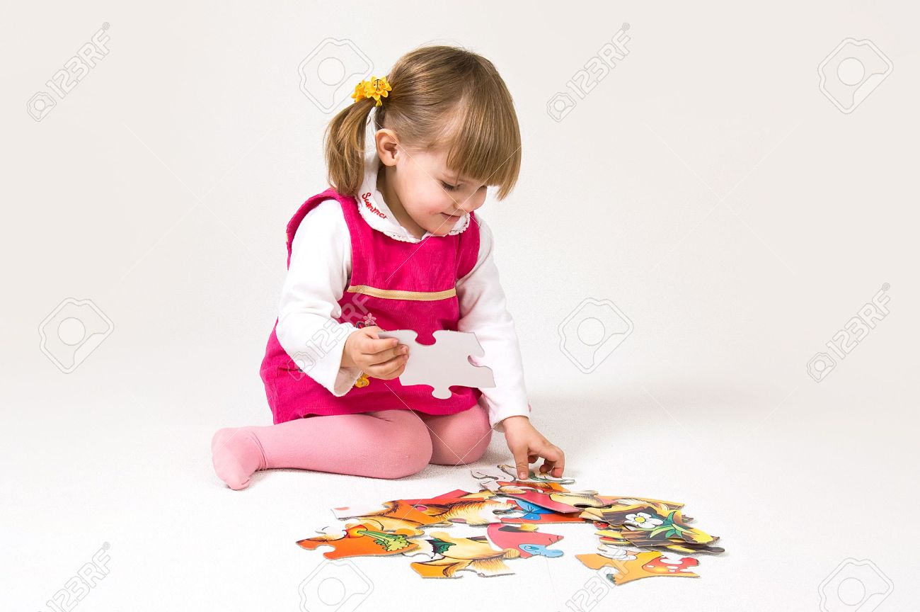 Little girl is solving puzzle on white background - 5727258 Little girl is solving puzzle on white background - 5727258
