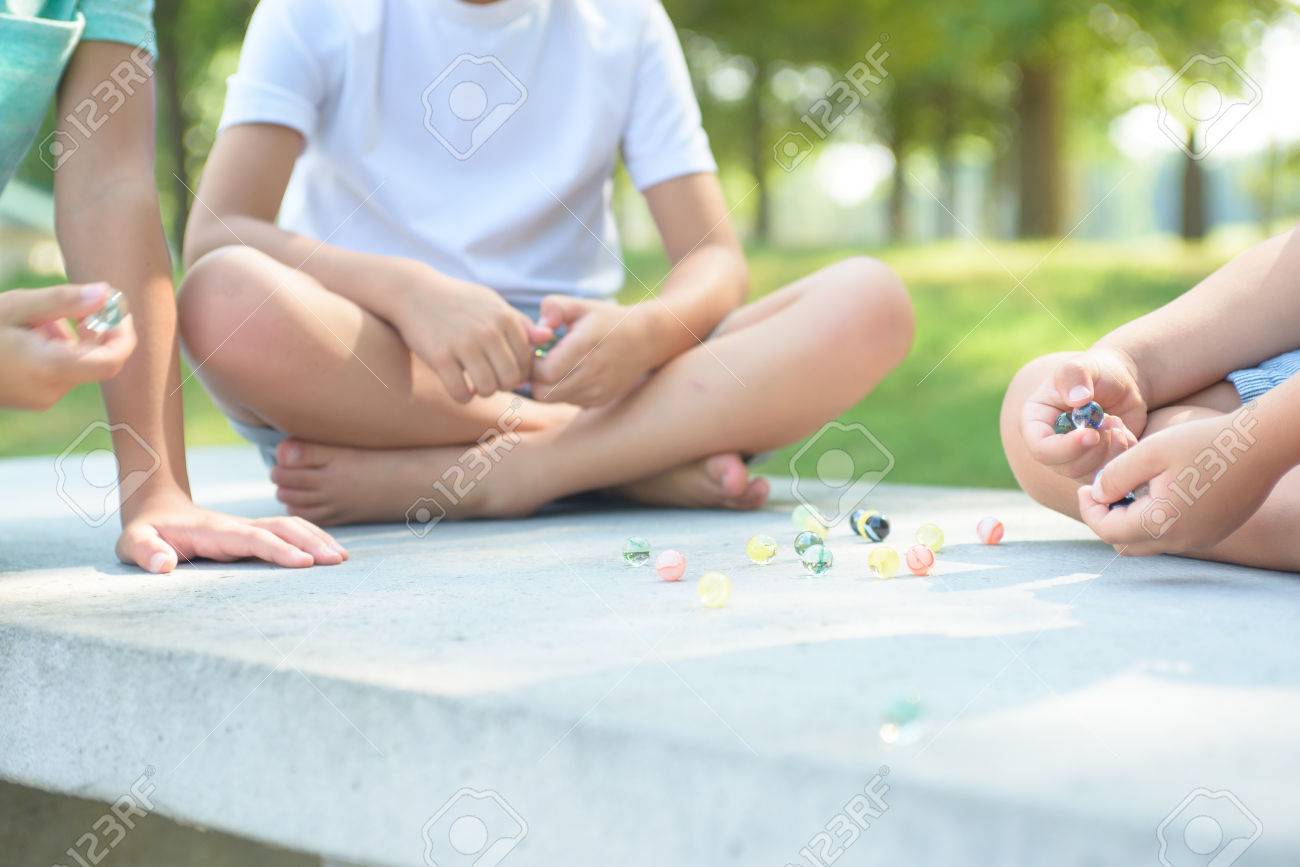Kids playing marbles game outside - 84187576 Kids playing marbles game outside - 84187576