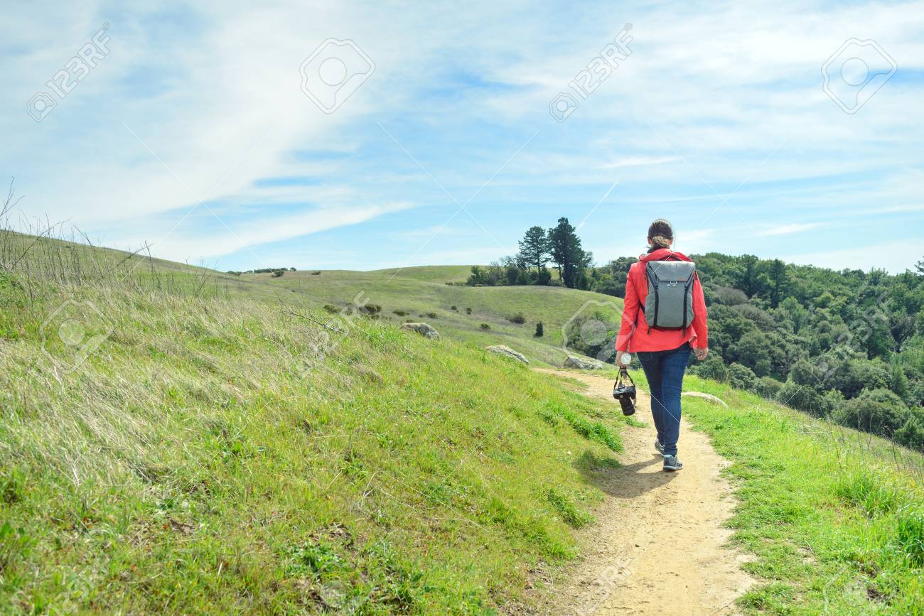 Hiker in red jacket with backpack on trail in beautiful landscape - 104878715 Hiker in red jacket with backpack on trail in beautiful landscape - 104878715