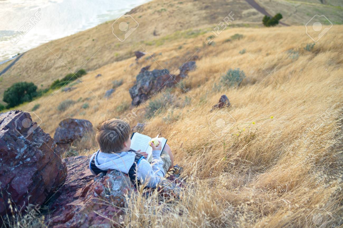 Boy reading book outside - 105112960 Boy reading book outside - 105112960