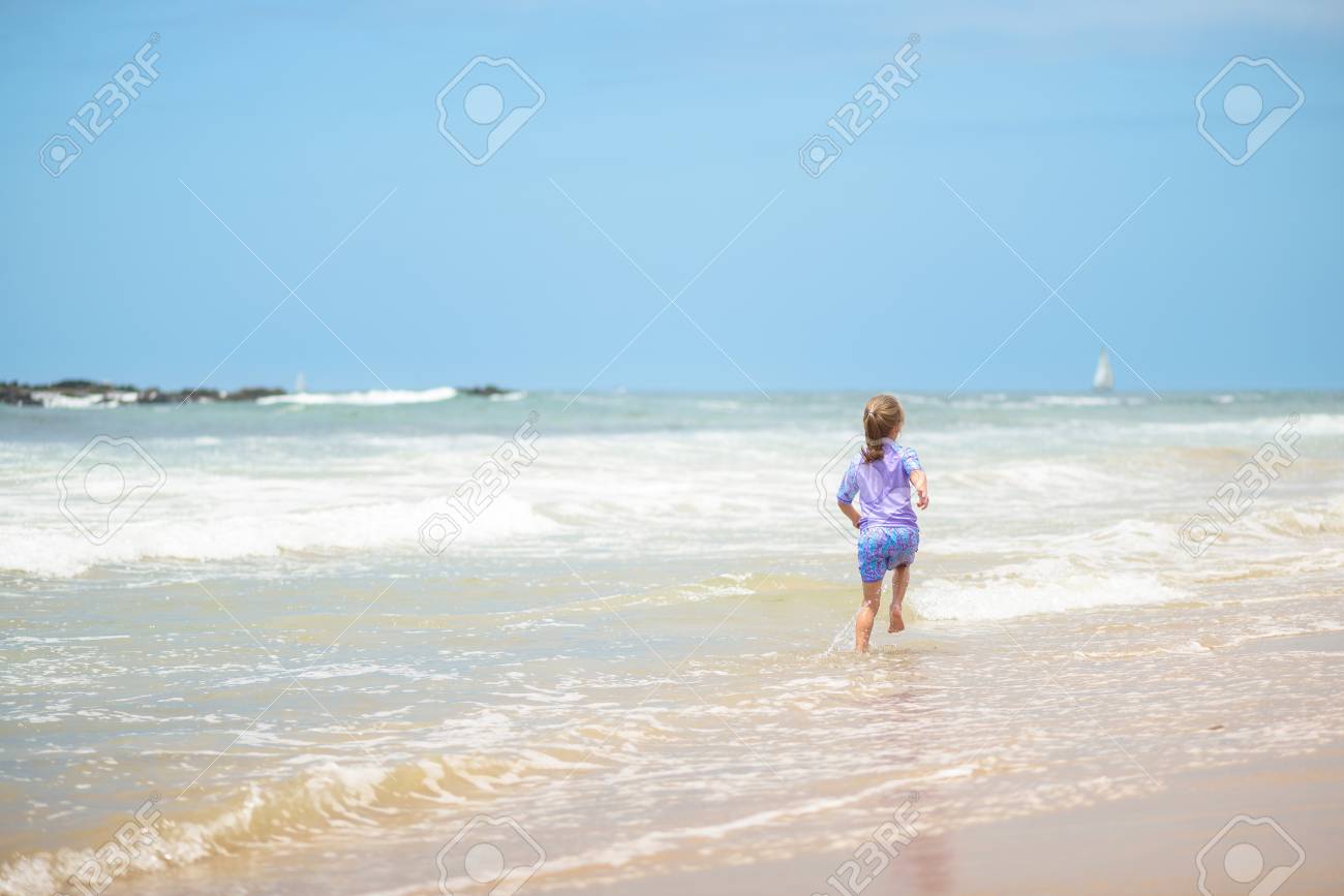 Happy girl running on the beach in the waves - 106235231 Happy girl running on the beach in the waves - 106235231