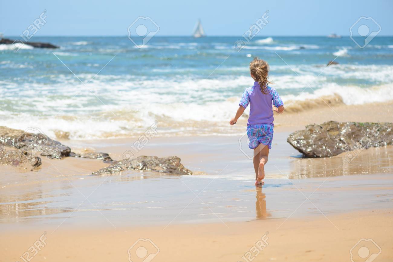 Happy girl running on the beach to the ocean - 106235232 Happy girl running on the beach to the ocean - 106235232