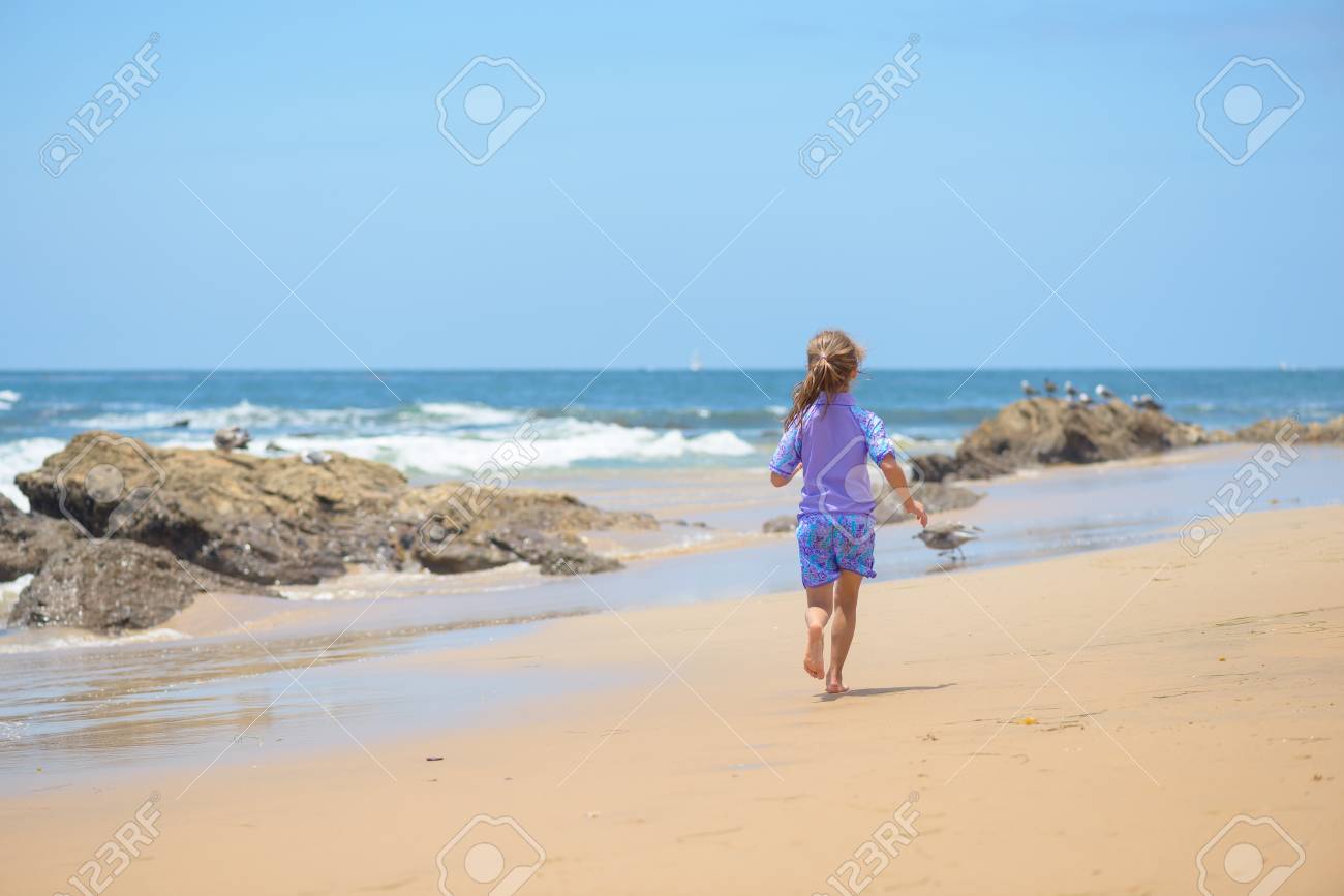 Happy girl running on the beach to the ocean - 106235235 Happy girl running on the beach to the ocean - 106235235
