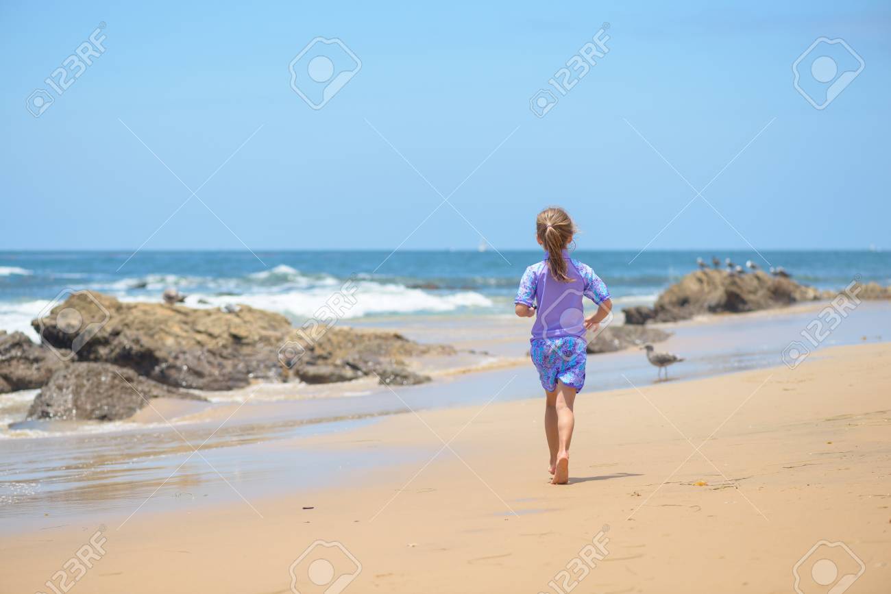 Happy girl running on the beach to the ocean - 106235239 Happy girl running on the beach to the ocean - 106235239