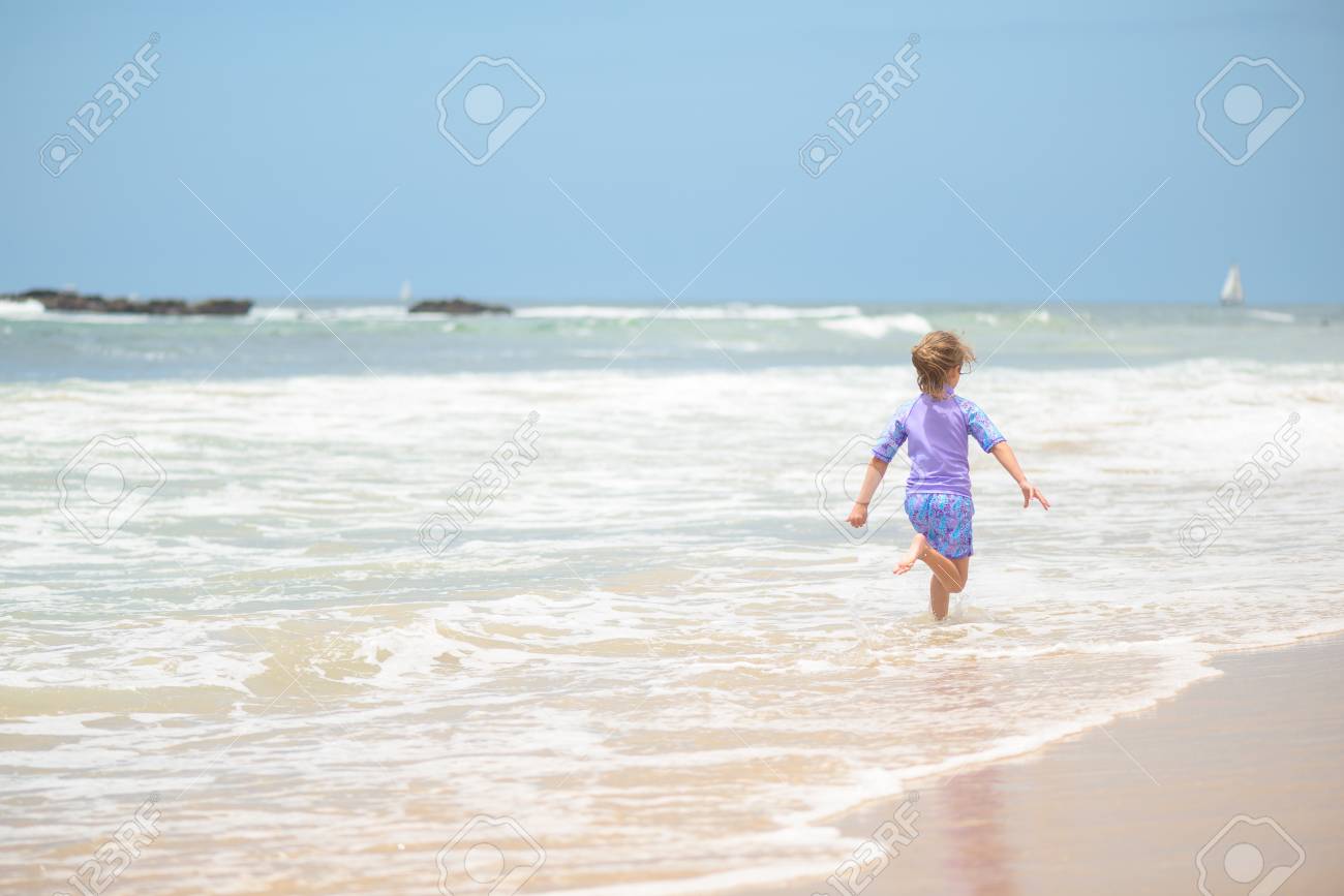 Happy girl running on the beach in the waves - 106235241 Happy girl running on the beach in the waves - 106235241