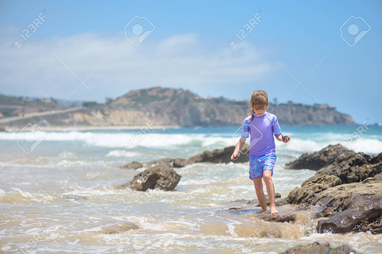 Happy girl playing on the beach in the rocks - 106235242 Happy girl playing on the beach in the rocks - 106235242