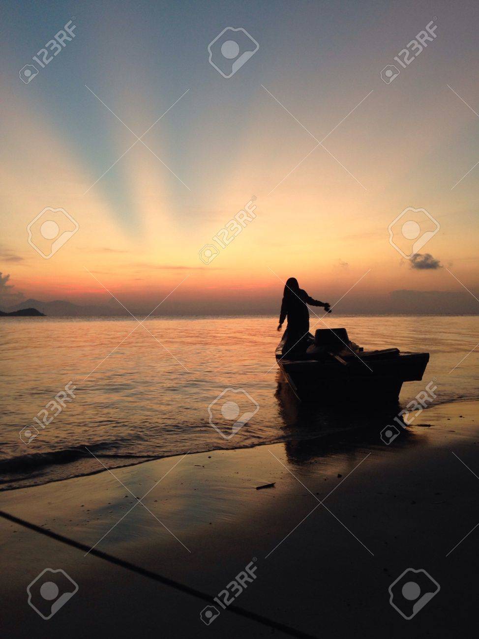 a woman standing on a boat eagerly waiting for the sunrise stock