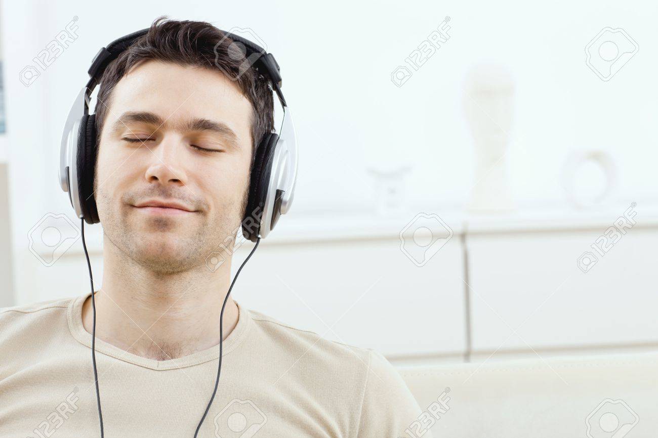 casual man listening music with headphones at home relaxing stock