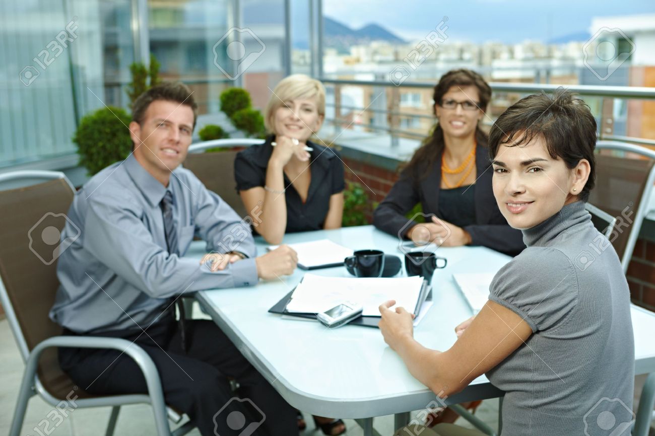 group of young business people sitting around table on office