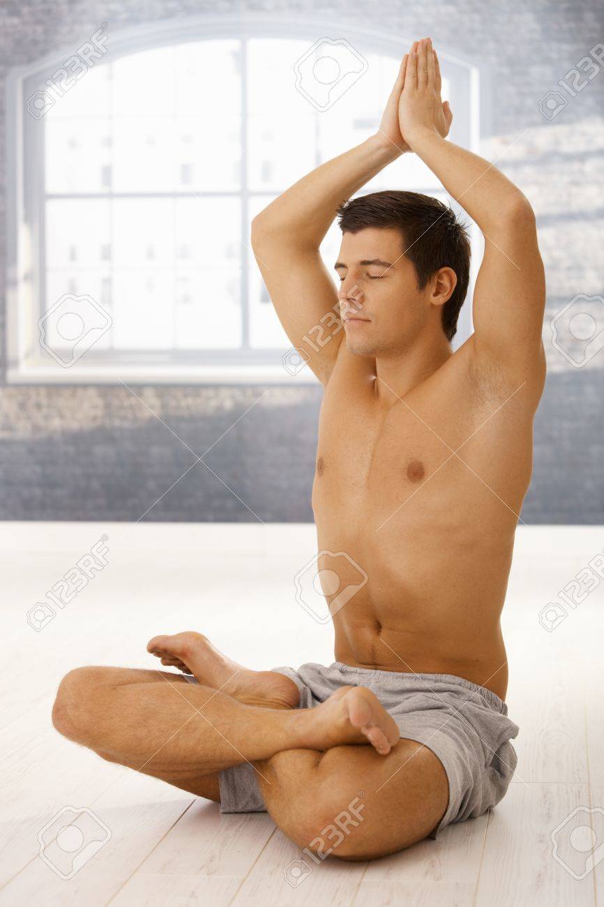 handsome sporty guy doing yoga meditation in lotus posture with