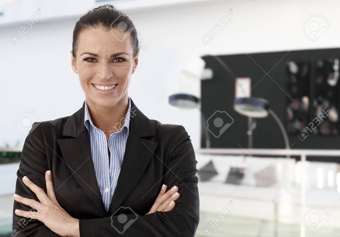 信頼できる女性ビジネス プロフェッショナル笑みを浮かべて 近代的なオフィスのロビーで立って腕組み の写真素材 画像素材 Image