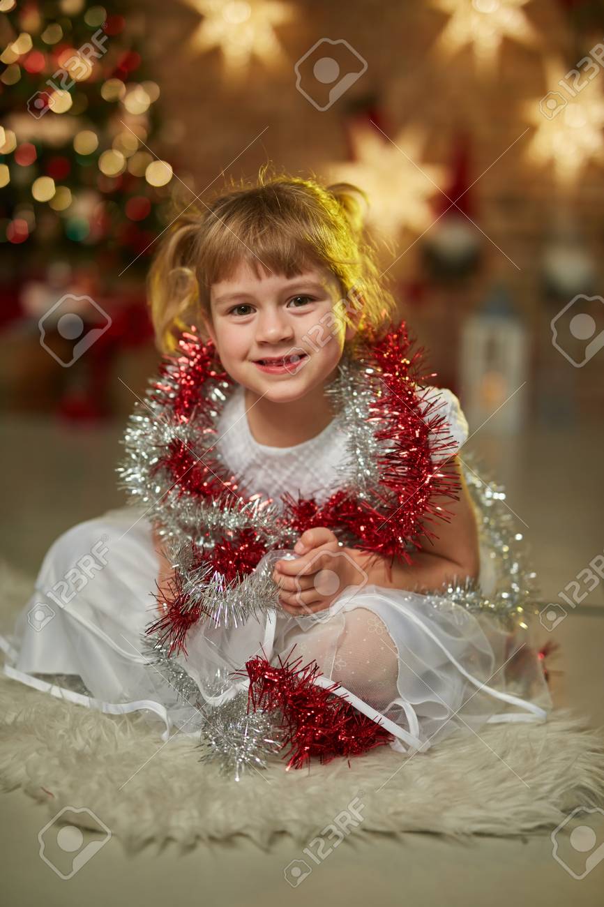 クリスマス 自宅のクリスマス ツリーの前で白いドレスの少女のための子供の肖像画 背景のクリスマス イルミネーション の写真素材 画像素材 Image