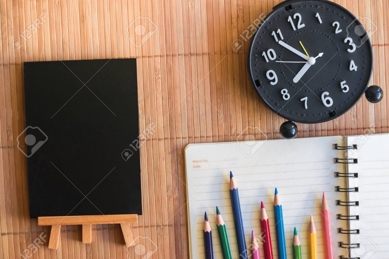 メモ帳 鉛筆と時計付きの黒板 木製ボードの背景にノートブック 教育のための壁紙 ビジネス写真を使用しています 紙とコンセプト オブジェクトまたはコピースペースを持つ本のための製品をメモしてください の写真素材 画像素材 Image