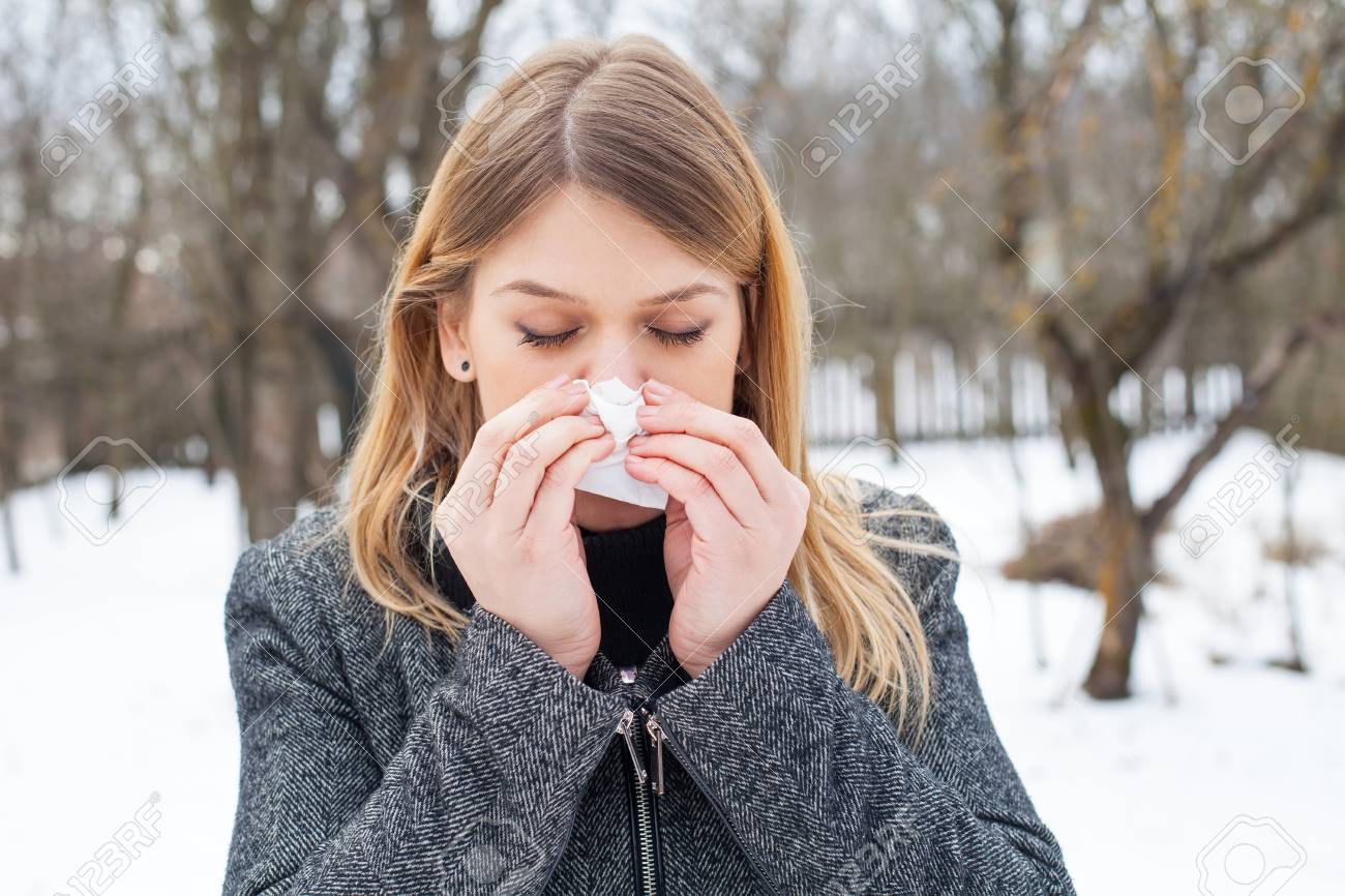 Picture of a sick young woman blowing her nose outdoor - 70759701 Picture of a sick young woman blowing her nose outdoor - 70759701