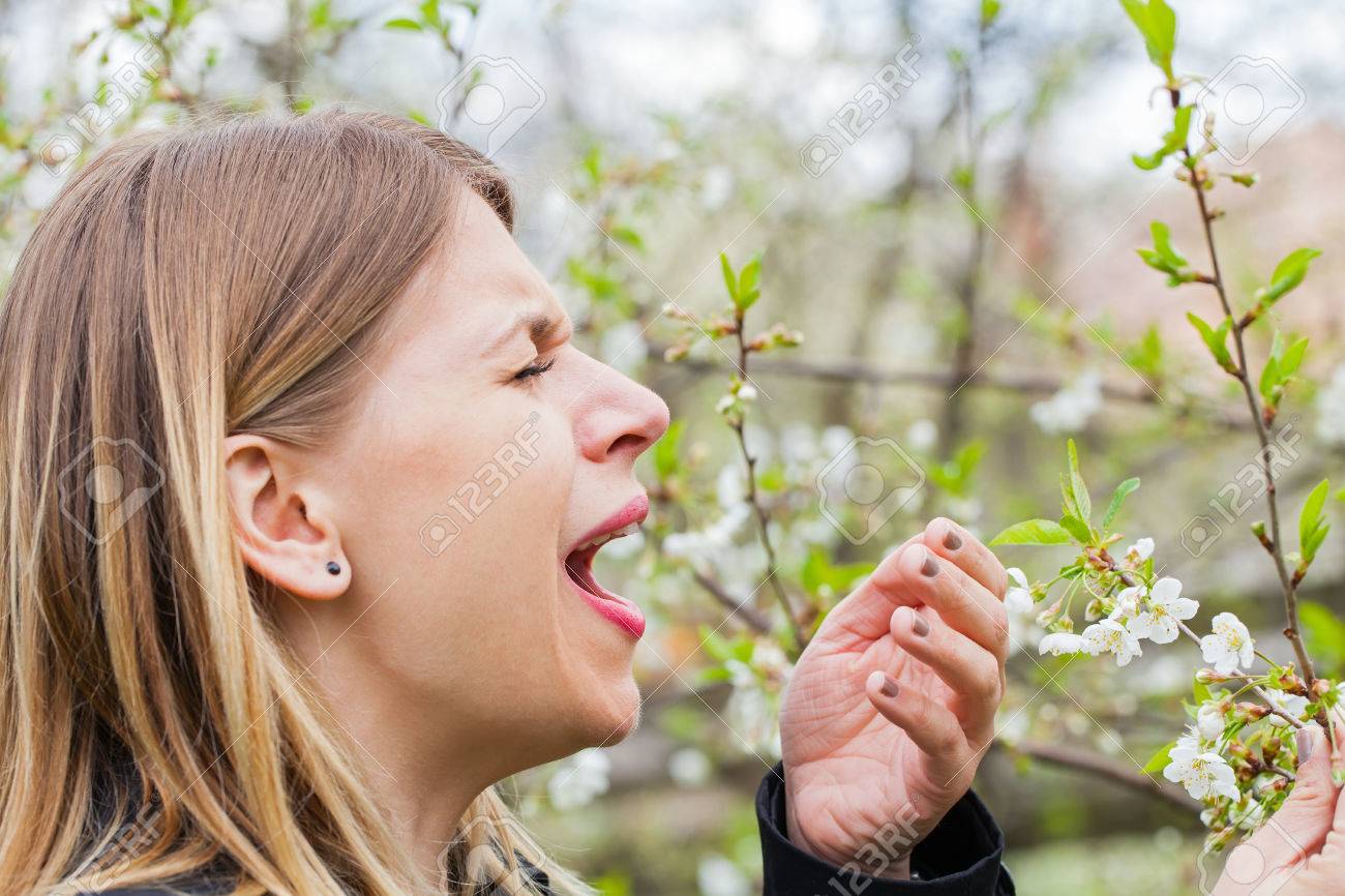 Young woman with allergy symptoms, sneezing, blowing her nose, springtime - 78573733 Young woman with allergy symptoms, sneezing, blowing her nose, springtime - 78573733