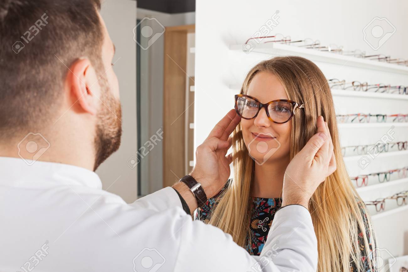 光学店で美しい若い女性のためのメガネフレームを選択するフレンドリーな男性眼科医 の写真素材 画像素材 Image
