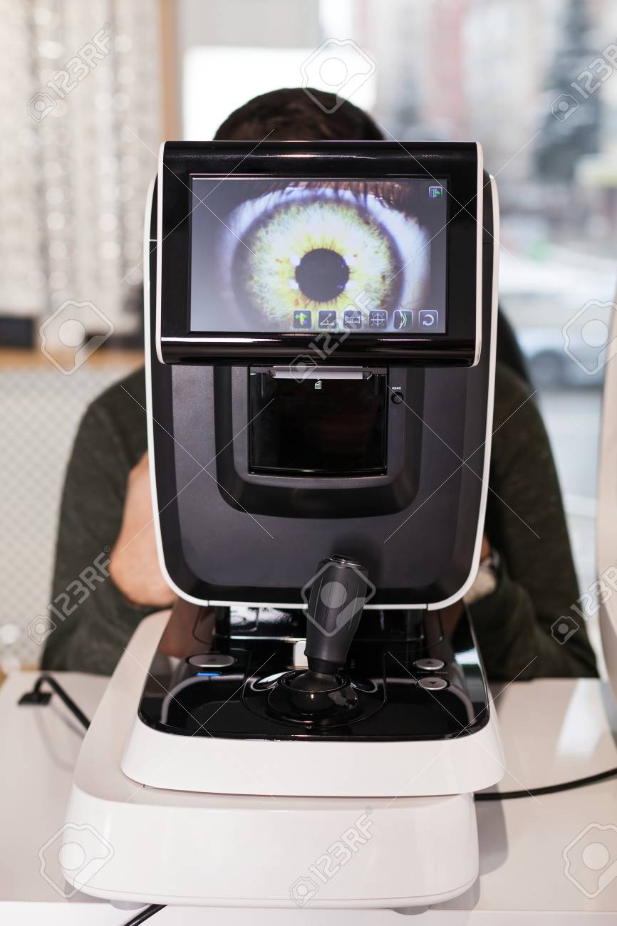 Ophthalmologist examining young man with optometric machine in optics store - 108692675 Ophthalmologist examining young man with optometric machine in optics store - 108692675