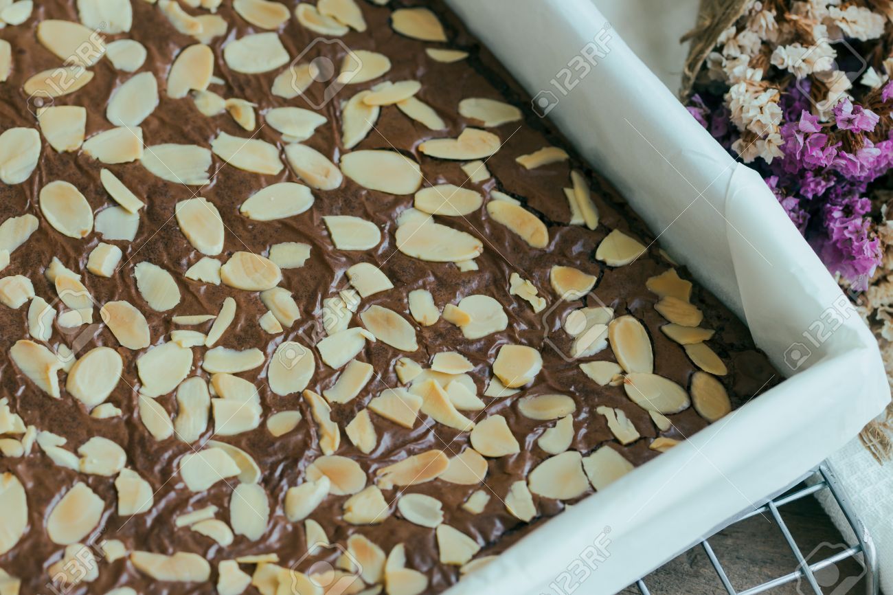 homemade dark chocolate brownies topping almond slices in square baking sheet cover