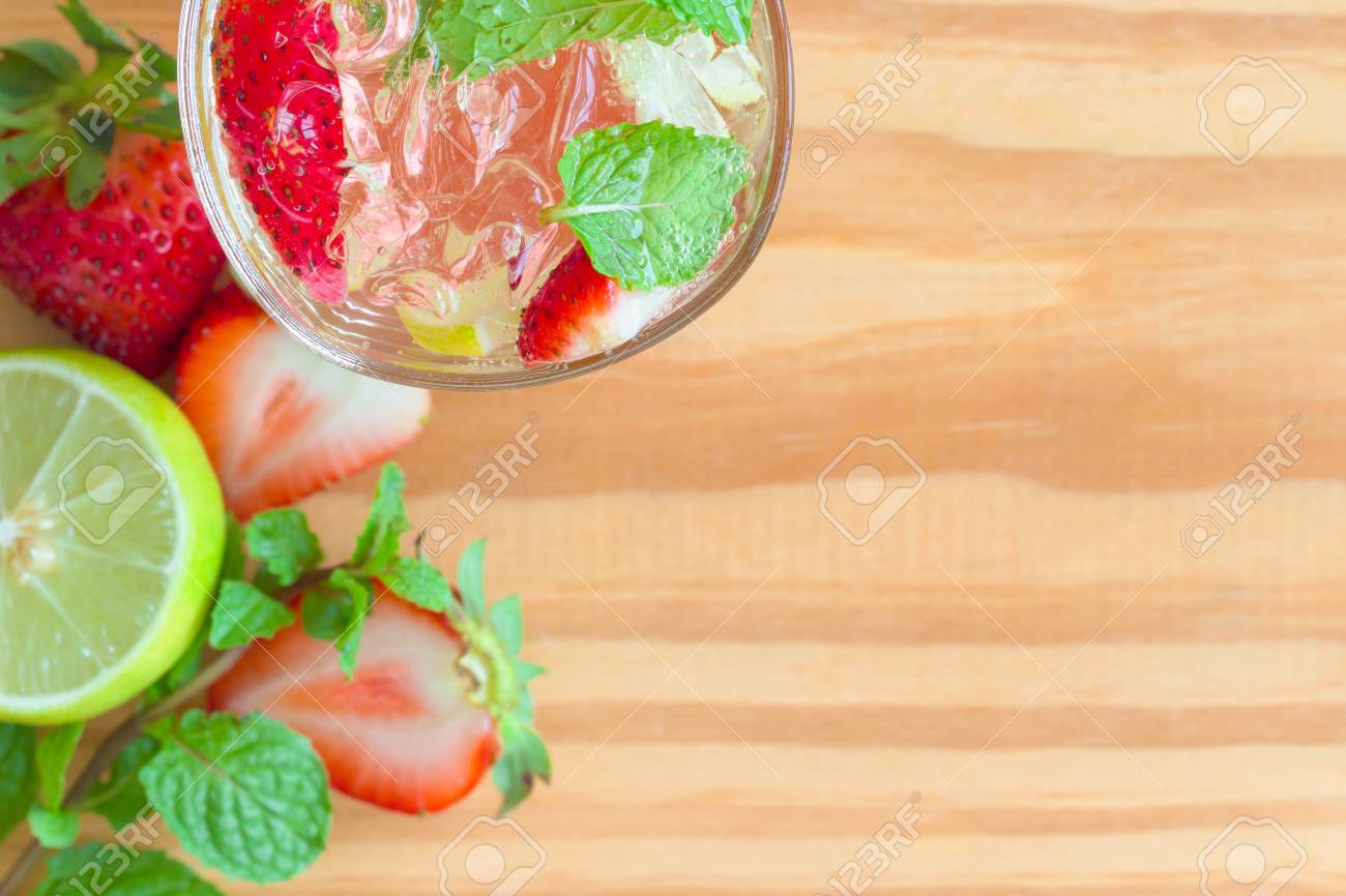 素朴な木製のテーブルの上の透明なガラスの上面イチゴ レモン ライム モヒート 水を注入 コピーの背景や壁紙のための領域とイチゴ レモンやライム ミントの葉で作られたいちごのソーダ の写真素材 画像素材 Image