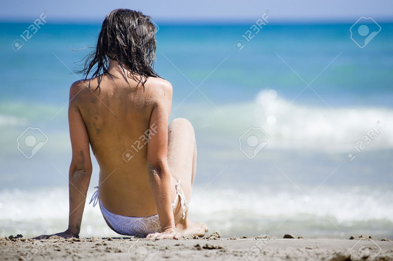 Mujer Desnuda Sentada Con La Espalda Frente A La Cámara, En La Arena Que  Llevaba Un Bikini Blanco Con El Mar En La Parte De Atrás Fotos, retratos,  imágenes y fotografía de