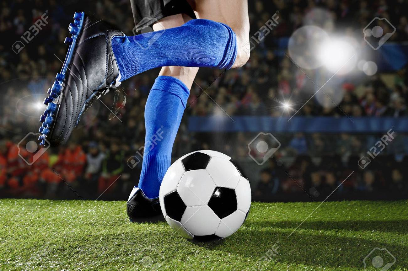Close Up Legs And Feet Of Football Player In Action Wearing Blue Socks And Black Shoes