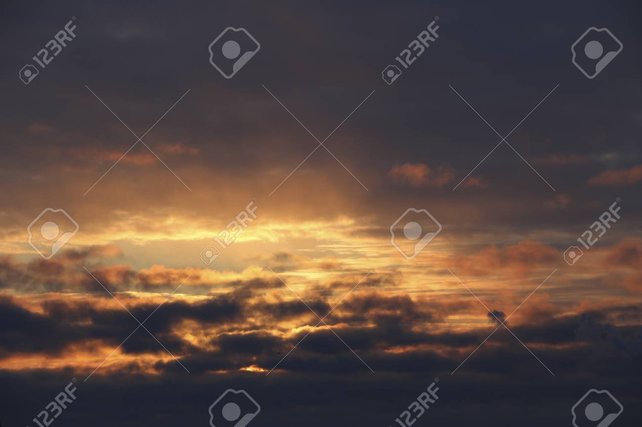 日没 濃い暗雲の中の夕方の冬の空 太陽は 日没時に冷ややかな空気と雲を通して明るい黄色の暖かい光を照らす の写真素材 画像素材 Image