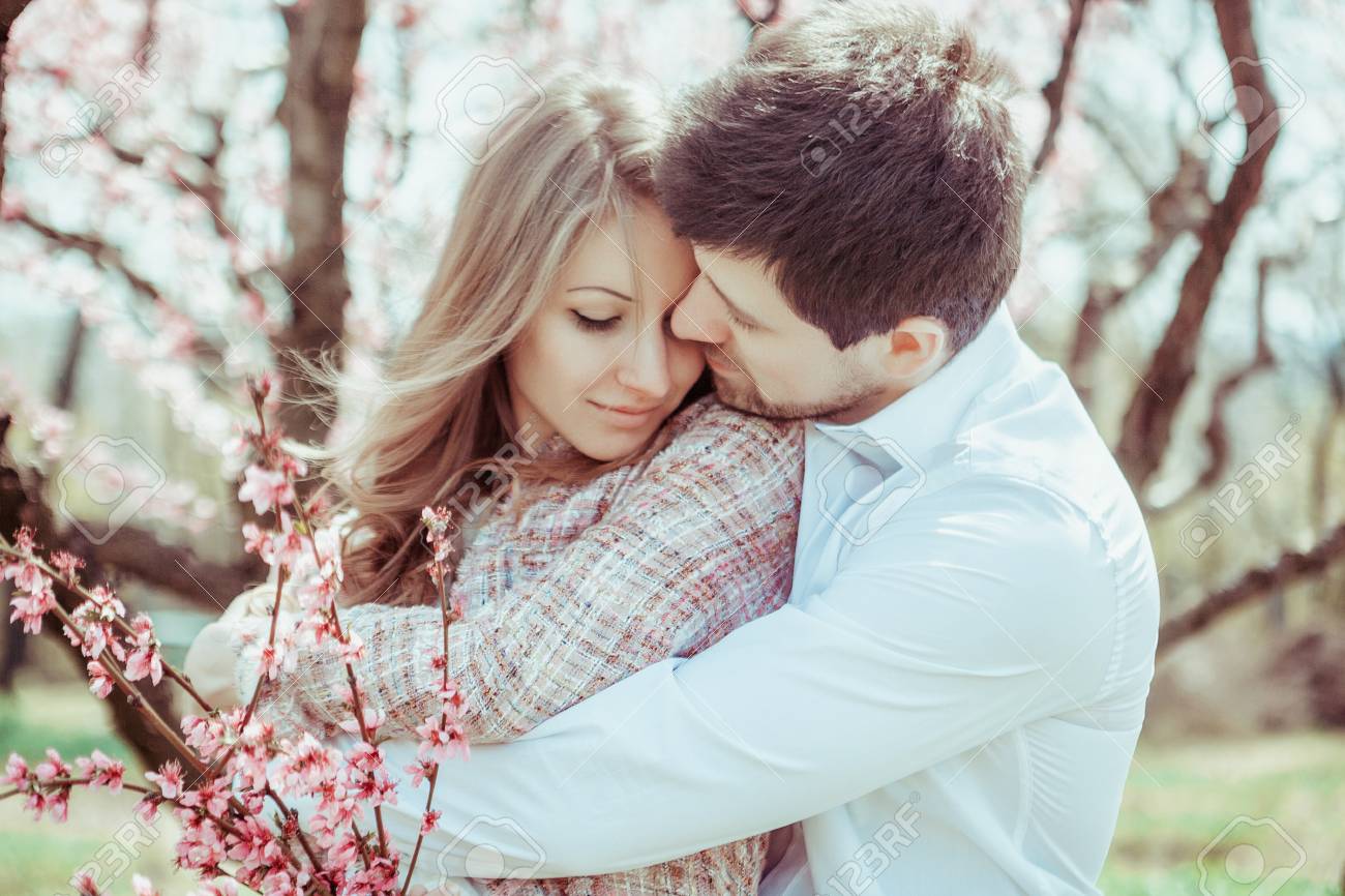 Joven Pareja De Novios En Un Jardín Floreciente. Tiernos Abrazados. Imagen  Al Aire Libre De La Familia Joven Cerca Del Manzano Floreciente. Amor Y  Ternura Fotos, Retratos, Imágenes Y Fotografía De Archivo
