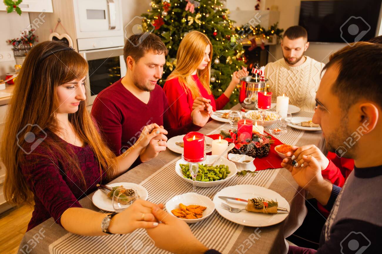 Young family and friends praying and blessing the table at christmas dinning - 139187281 Young family and friends praying and blessing the table at christmas dinning - 139187281